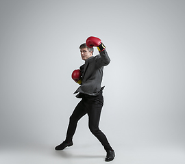 Image showing Caucasian man in office clothes boxing isolated on grey studio background