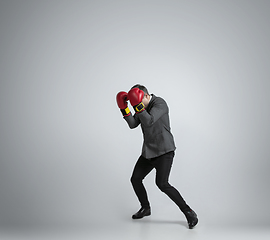 Image showing Caucasian man in office clothes boxing isolated on grey studio background