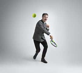 Image showing Caucasian man in office clothes plays tennis isolated on grey studio background