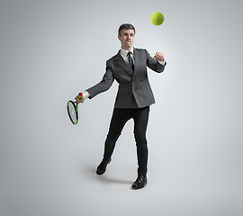 Image showing Caucasian man in office clothes plays tennis isolated on grey studio background