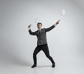 Image showing Caucasian man in office clothes plays badminton isolated on grey studio background