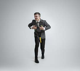 Image showing Caucasian man in office clothes plays tennis isolated on grey studio background