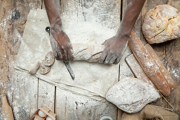 Image showing Top view of african-american man cooks bread at craft kitchen