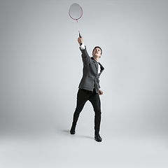 Image showing Caucasian man in office clothes plays badminton isolated on grey studio background