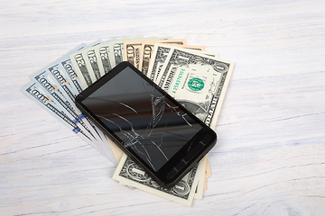 Image showing cracked cellular phone and American money on white
