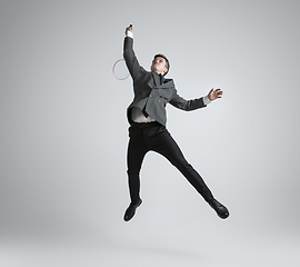 Image showing Caucasian man in office clothes plays badminton isolated on grey studio background