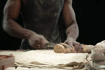 Image showing Close up of african-american man slices fresh bread with a kitchen knife