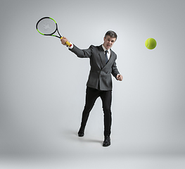 Image showing Caucasian man in office clothes plays tennis isolated on grey studio background