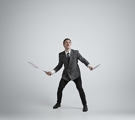 Image showing Caucasian man in office clothes plays badminton isolated on grey studio background