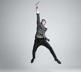 Image showing Caucasian man in office clothes plays badminton isolated on grey studio background