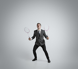 Image showing Caucasian man in office clothes plays badminton isolated on grey studio background