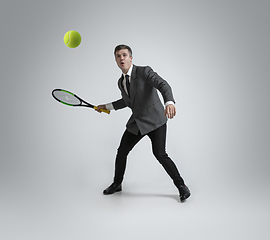 Image showing Caucasian man in office clothes plays tennis isolated on grey studio background