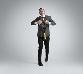 Image showing Caucasian man in office clothes plays tennis isolated on grey studio background