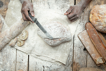Image showing Top view of african-american man cooks bread at craft kitchen