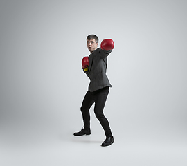 Image showing Caucasian man in office clothes boxing isolated on grey studio background