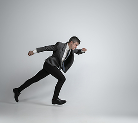 Image showing Caucasian man in office clothes running isolated on grey studio background