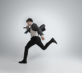 Image showing Caucasian man in office clothes running isolated on grey studio background