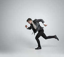 Image showing Caucasian man in office clothes running isolated on grey studio background