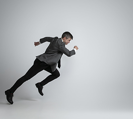 Image showing Caucasian man in office clothes running isolated on grey studio background