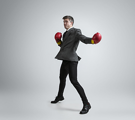 Image showing Caucasian man in office clothes boxing isolated on grey studio background