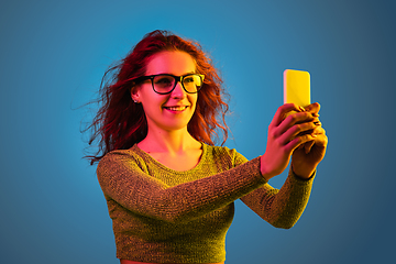 Image showing Caucasian woman\'s portrait isolated on blue studio background in neon light