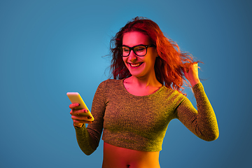 Image showing Caucasian woman\'s portrait isolated on blue studio background in neon light