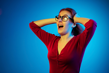 Image showing Caucasian woman\'s portrait isolated on blue studio background in neon light