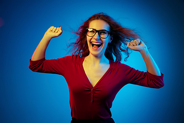 Image showing Caucasian woman\'s portrait isolated on blue studio background in neon light