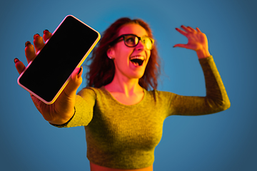 Image showing Caucasian woman\'s portrait isolated on blue studio background in neon light