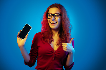 Image showing Caucasian woman\'s portrait isolated on blue studio background in neon light