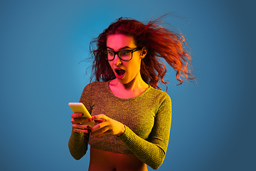 Image showing Caucasian woman\'s portrait isolated on blue studio background in neon light