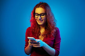 Image showing Caucasian woman\'s portrait isolated on blue studio background in neon light