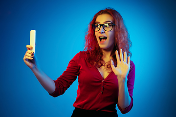 Image showing Caucasian woman\'s portrait isolated on blue studio background in neon light