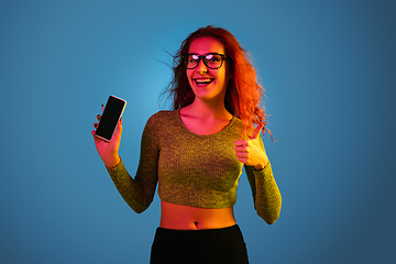 Image showing Caucasian woman\'s portrait isolated on blue studio background in neon light