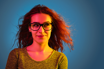 Image showing Caucasian woman\'s portrait isolated on blue studio background in neon light