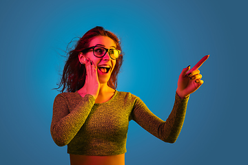 Image showing Caucasian woman\'s portrait isolated on blue studio background in neon light