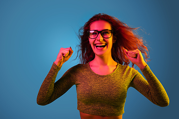 Image showing Caucasian woman\'s portrait isolated on blue studio background in neon light