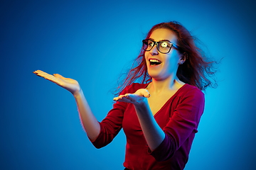 Image showing Caucasian woman\'s portrait isolated on blue studio background in neon light