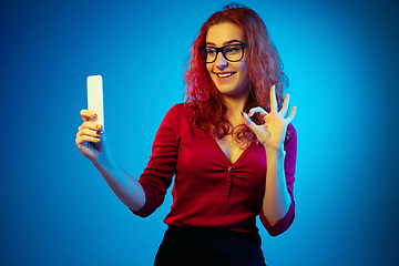 Image showing Caucasian woman\'s portrait isolated on blue studio background in neon light