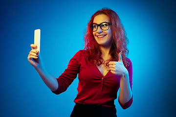 Image showing Caucasian woman\'s portrait isolated on blue studio background in neon light