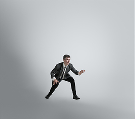 Image showing Caucasian man in office clothes training isolated on grey studio background