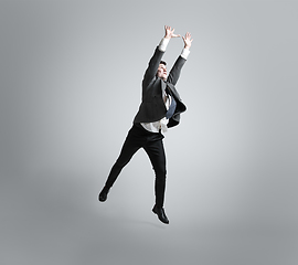 Image showing Caucasian man in office clothes training isolated on grey studio background