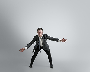 Image showing Caucasian man in office clothes training isolated on grey studio background