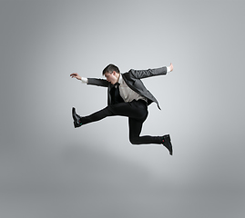 Image showing Caucasian man in office clothes running isolated on grey studio background