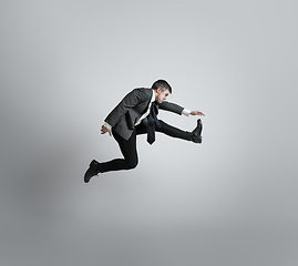 Image showing Caucasian man in office clothes running isolated on grey studio background