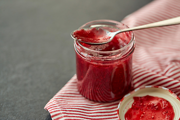 Image showing mason jar with raspberry jam and spoon on towel