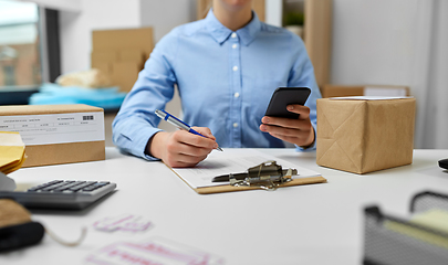 Image showing woman with smartphone and clipboard at post office