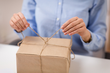 Image showing woman packing parcel or gift box and tying rope