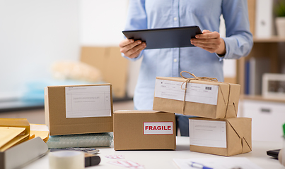 Image showing woman with tablet pc and parcels at post office