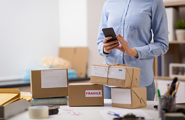 Image showing woman with smartphone and parcels at post office